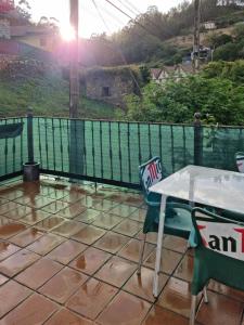een patio met een tafel en stoelen op een balkon bij Corias Casona junto al Narcea in Corias