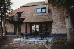 uma casa de tijolos com mesas e cadeiras e uma janela em Eikenhoef em Lommel