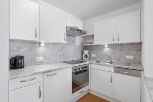 a white kitchen with white cabinets and a sink at Haus Aventurin in Fiss