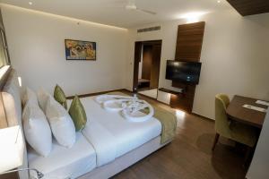 ein Hotelzimmer mit einem Bett und einem TV in der Unterkunft Woodbine Foliage in Malappuram