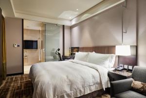 una habitación de hotel con una cama grande y una silla en The Tango Hotel Taipei Nanshi, en Taipéi