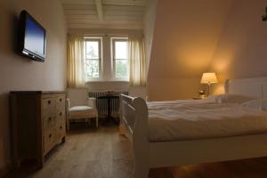 1 dormitorio con 1 cama y TV en la pared en Ruhiges Landhaus Krienke - Doppelhaus mit Sauna & Kamin, en Rankwitz