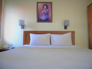1 cama con 2 almohadas y una foto en la pared en Pia Hotel, en Cirebon