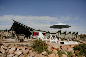 a couple of chairs and an umbrella in front of a building at Sea Shack in Paternoster