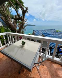 una mesa blanca y sillas en un balcón con vistas al océano en Sunset Seaview Patong en Patong Beach