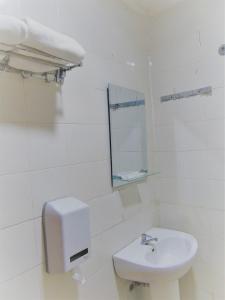 Baño blanco con lavabo y espejo en Pia Hotel, en Cirebon