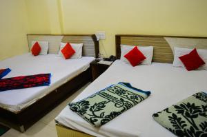 2 Betten in einem Zimmer mit roten und blauen Kissen in der Unterkunft Hotel Bholenath Palace in Ujjain