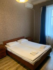 a bedroom with a bed with white sheets and a window at Apart-Hotel City Center Contrabas in Lviv