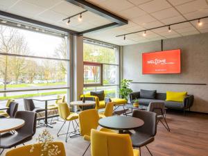 una sala de espera con mesas y sillas amarillas en ibis Hotel Dortmund City, en Dortmund