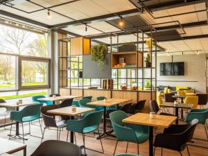 un restaurante con mesas, sillas y ventanas en ibis Hotel Dortmund City, en Dortmund