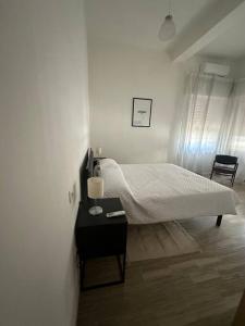 Dormitorio blanco con cama y mesa con lámpara en Casa Giuliana, en Montesilvano