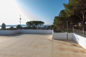 a large patio with a white wall and trees at L'isola di Gianni by Ortigia Apartments in Plemmirio