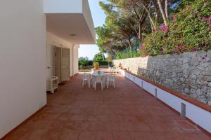 a patio with tables and chairs and a stone wall at L'isola di Gianni by Ortigia Apartments in Plemmirio