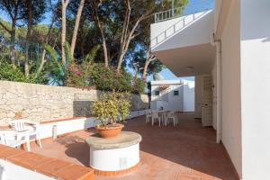 a patio with tables and chairs and a stone wall at L'isola di Gianni by Ortigia Apartments in Plemmirio