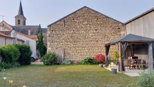 un patio trasero con cenador y un edificio de ladrillo en Gite Amanala Poitou, en Saint-Genest-dʼAmbière