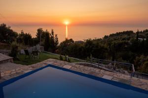 a swimming pool with a sunset in the background at Sun And Stone in Athani