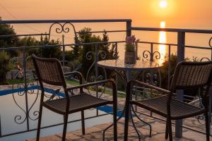 a table and chairs on a balcony with the sunset at Sun And Stone in Athani