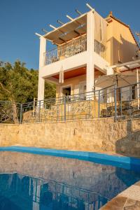 a villa with a swimming pool in front of a house at Sun And Stone in Athani
