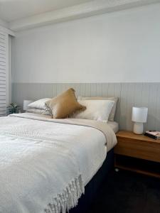 1 dormitorio con 1 cama con sábanas blancas y lámpara en 8th Floor Sunny Escape at Landmark Resort en Mooloolaba