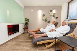 two people sitting on chairs in a living room with a fireplace at Apartmány Engadin in Boží Dar