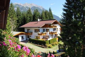 ein Haus mit Garten und Bergen im Hintergrund in der Unterkunft Haus Moosplatzl in Leutasch