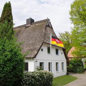 uma bandeira arvorando em frente a uma casa com um telhado em Ferienwohnung am Sandbarg em Jesteburg