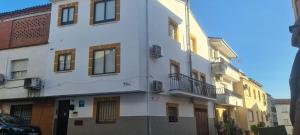 a white building with windows and a car parked in front at APARTAMENTOS DAYMA in Jarandilla de la Vera