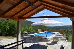 Stolac的住宿－Kamena Oaza，一个带桌子和遮阳伞的庭院和一个游泳池
