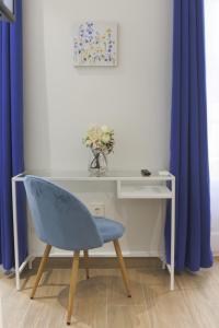 einen Schreibtisch mit einem blauen Stuhl in einem Zimmer mit blauen Vorhängen in der Unterkunft Dorinda Rooms in Alicante