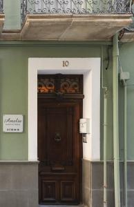 eine Holztür in einem Gebäude mit einem Schild darüber in der Unterkunft Dorinda Rooms in Alicante