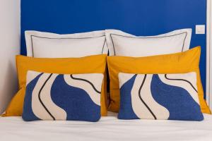 a bed with three pillows and a blue wall at Chic appartement proche métro in Paris