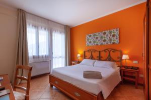 a bedroom with an orange wall with a bed and a chair at iH Hotels Le Zagare Resort in Villasimius