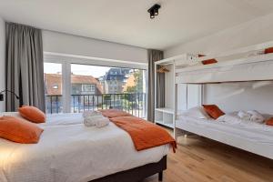 a bedroom with two beds and a large window at Strandparel luxueus duplex appartement met 2 terrassen én parking in Koksijde