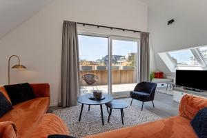 uma sala de estar com um sofá e uma mesa em Strandparel luxueus duplex appartement met 2 terrassen én parking em Koksijde