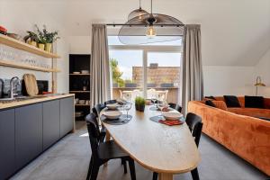 a kitchen and living room with a table and a couch at Strandparel luxueus duplex appartement met 2 terrassen én parking in Koksijde