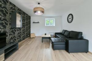 uma sala de estar com um sofá preto e uma mesa em Au 2 ailes - Charmante maison pour 7 em Picauville