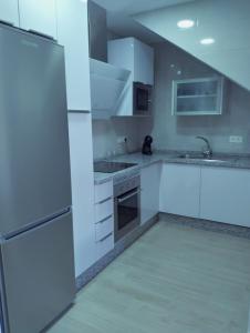uma cozinha com armários brancos e um frigorífico em Casa Margarita Confort em Ardales