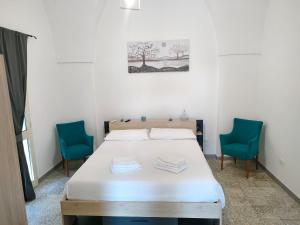 a bedroom with a bed and two blue chairs at Casa di nonna Uccia in Casamassella +1 photo