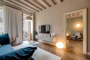 a living room with a blue couch and a television at Mercatovecchio Luxury Apartments in Udine