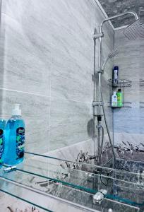 a shower with a blue bottle on a glass counter at Hotel Sunny in Akhaltsikhe