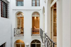 a woman sitting on a balcony of a white building at Mercatovecchio Luxury Apartments in Udine