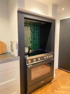 a kitchen with a stove with a green tiled wall at Parkzicht in Leeuwarden
