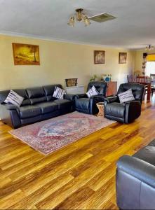 a living room with black leather couches and a wooden floor at Diggers Dealers Accommodation in Kalgoorlie