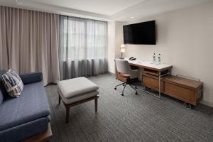 a hotel room with a desk and a couch and a chair at Courtyard by Marriott Seattle Bellevue/Downtown in Bellevue