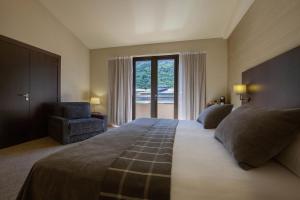 een slaapkamer met een groot bed en een groot raam bij Hotel Màgic Andorra in Andorra la Vella