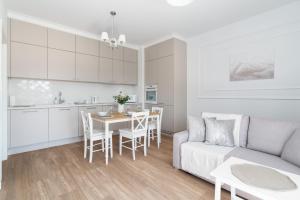 a living room and kitchen with a couch and a table at White Elegance Apartment with AC & FREE GARAGE by Renters in Poznań