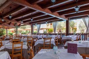 una sala da pranzo con tavoli e sedie bianchi di iH Hotels Le Zagare Resort a Villasimius