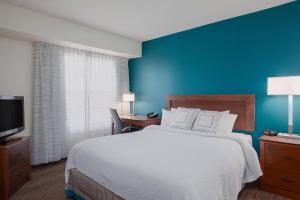 1 dormitorio con 1 cama grande y pared azul en Residence Inn by Marriott Laredo Del Mar, en Laredo