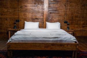 1 cama con sábanas blancas y almohadas en una habitación en Ethno Sazano Hotel, en Sazano