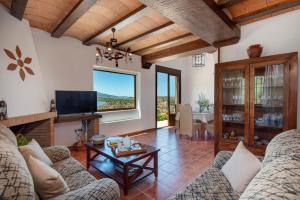 ein Wohnzimmer mit Sofas, einem TV und einem Tisch in der Unterkunft El Huertecillo by Vintage Travel in El Gastor